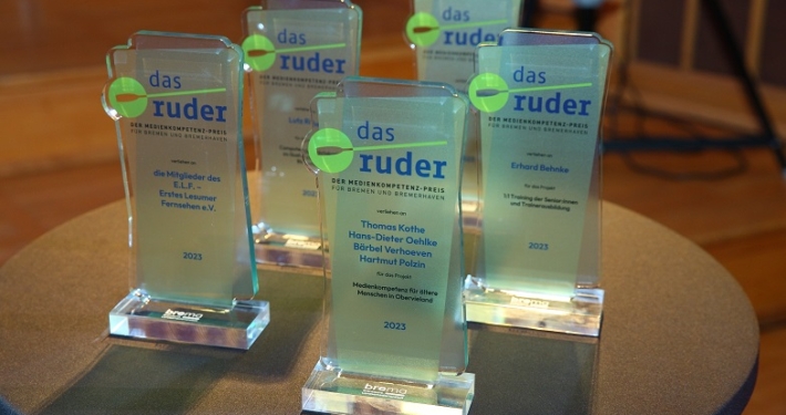 Mehrere identische Awards aus Glas stehen auf einem runden Tisch.