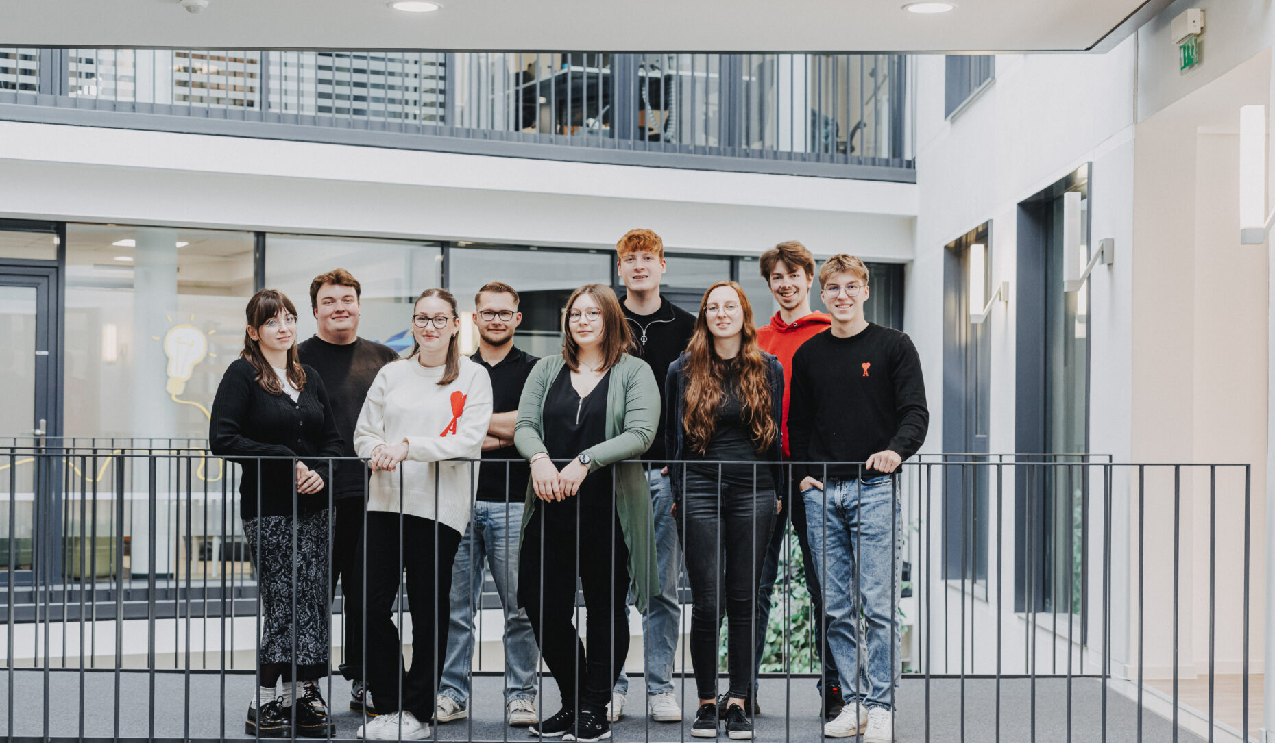 Gruppenfoto von 9 Personen, die an einem Geländer stehen.