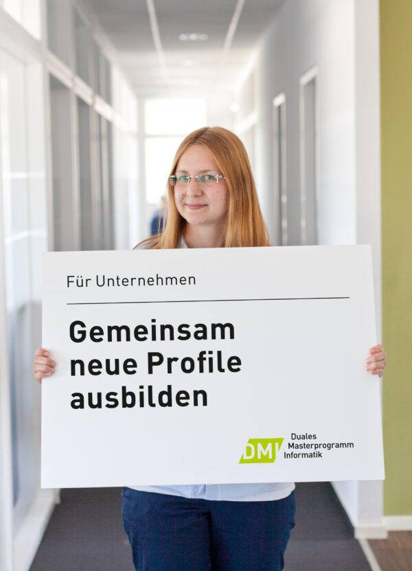 Eine Frau hält ein Plakat hoch, auf dem steht: Gemeinsam neue Profile ausbilden.