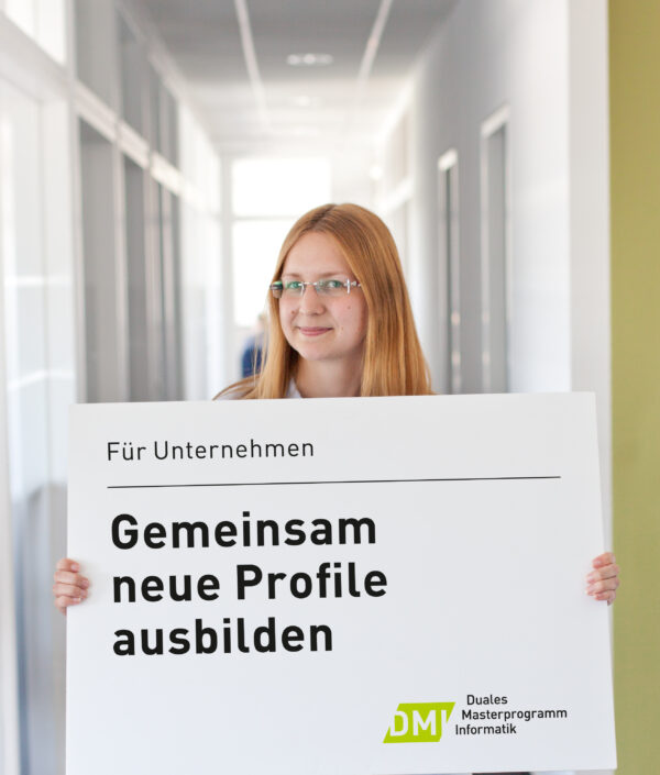 Eine Frau hält ein Plakat hoch, auf dem steht: Gemeinsam neue Profile ausbilden.